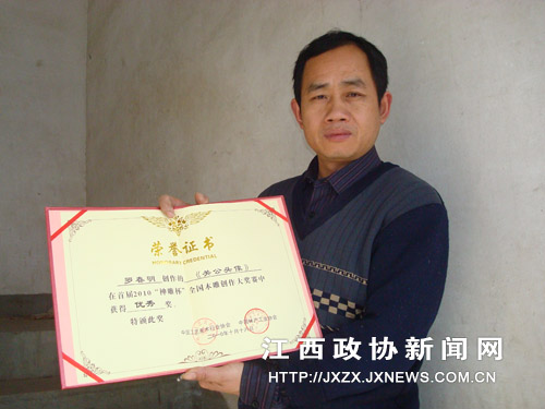罗春明在展示今年10月参加首届2010‘神雕杯’全国木雕创作大奖赛”获奖荣誉证书