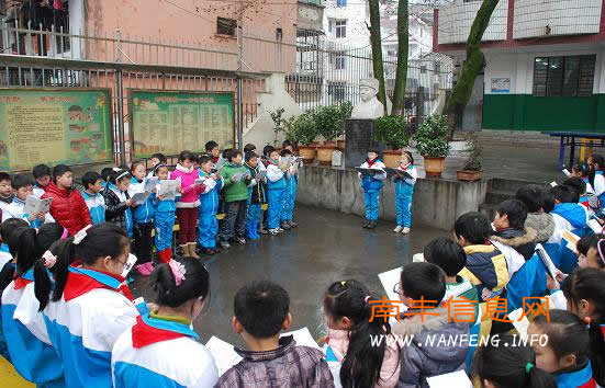 附小学生在雷锋塑像前读雷锋故事