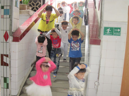 县幼儿园幼儿在老师指导下进行防地震安全演练